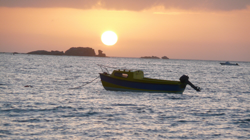 Sunset looking out to sea with a small boat in the foreground